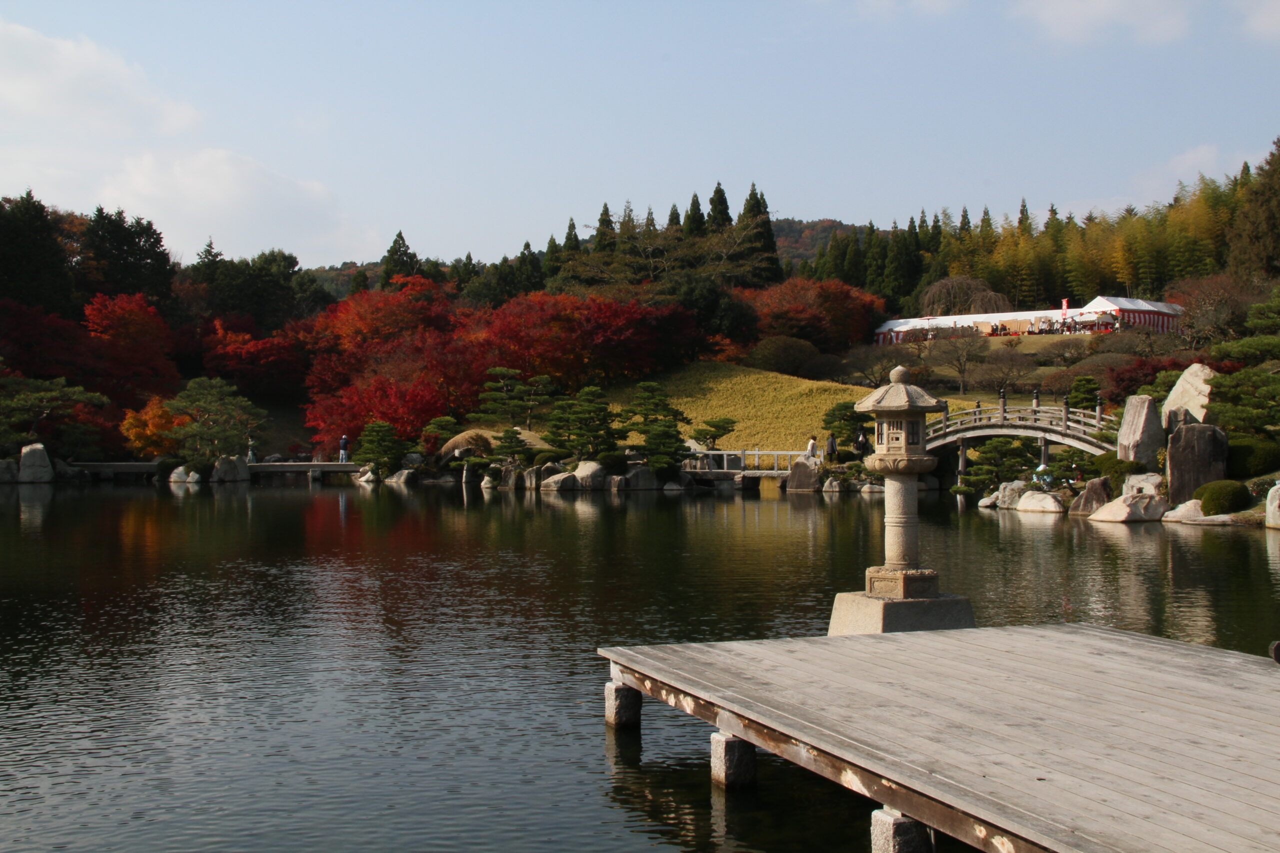 Autumn landscape of Sankei-en Japanese garden with arched bridge and reflections near Hiroshima Airport